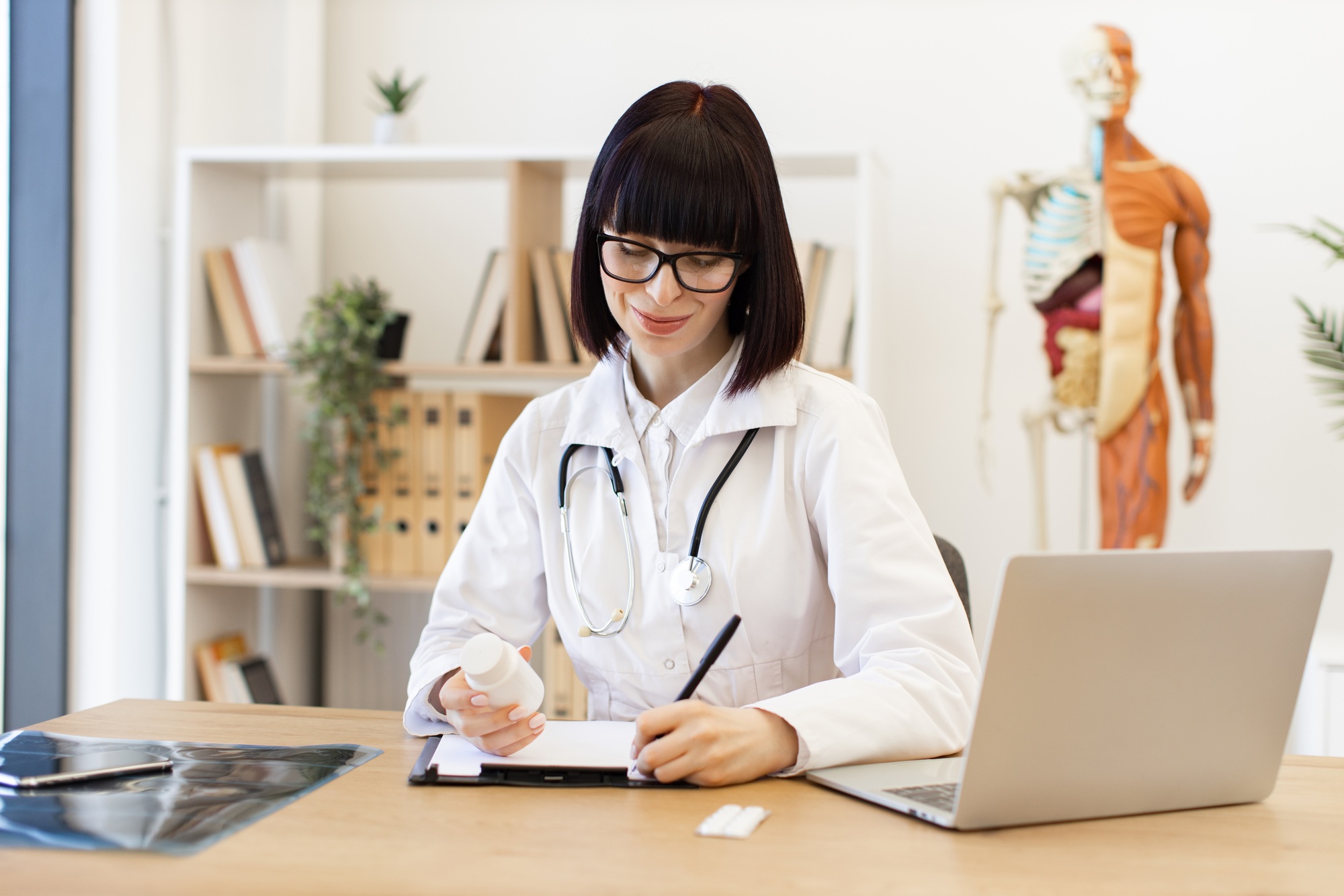 Female doctor writing prescription in medical office